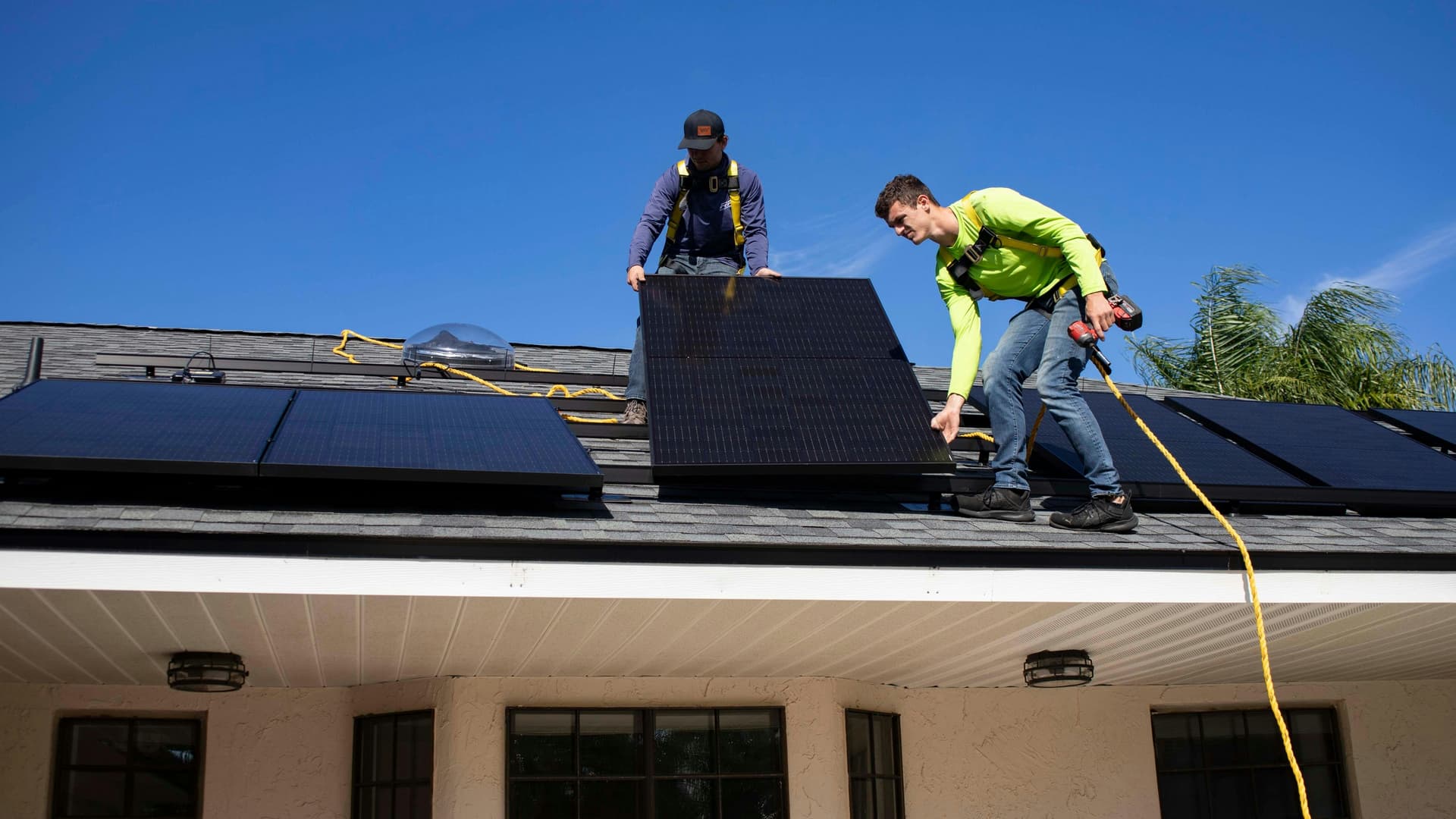 Installers fitting solar panels on a residential rooftop